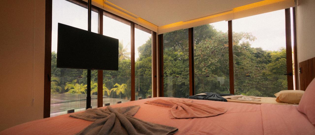 Bedroom with large windows overlooking a lush forest