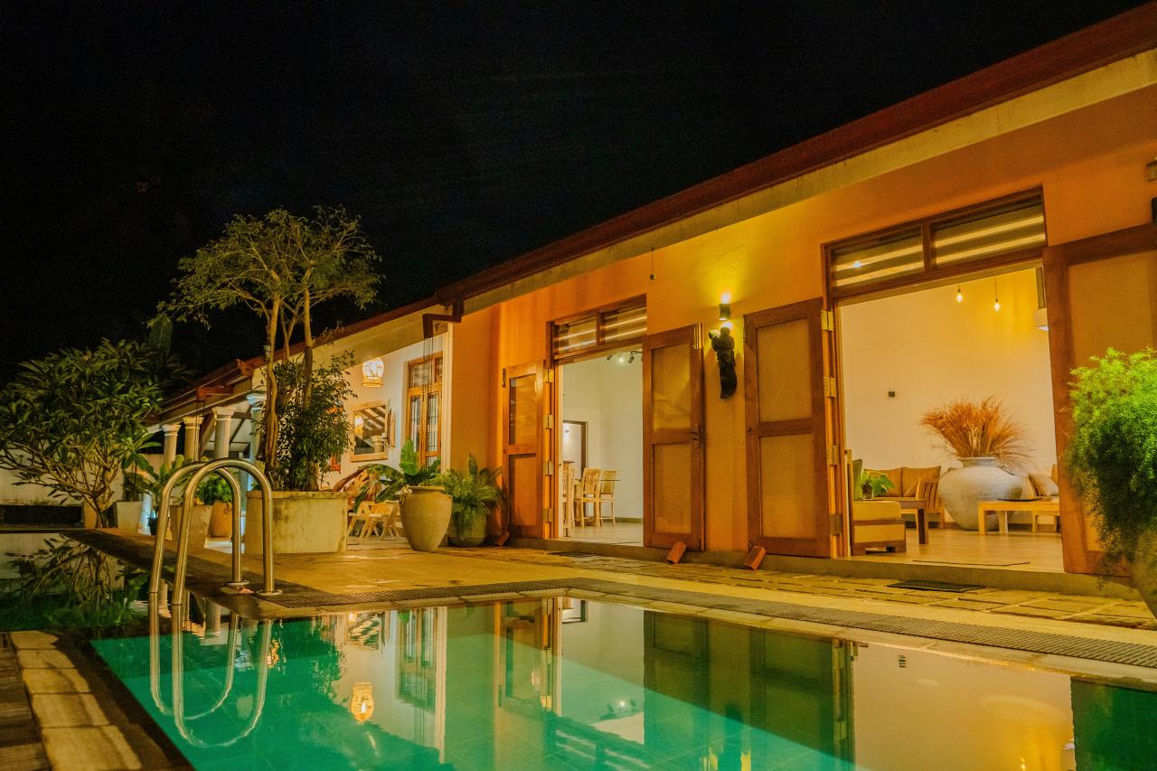 A lit-up pool and house at night.